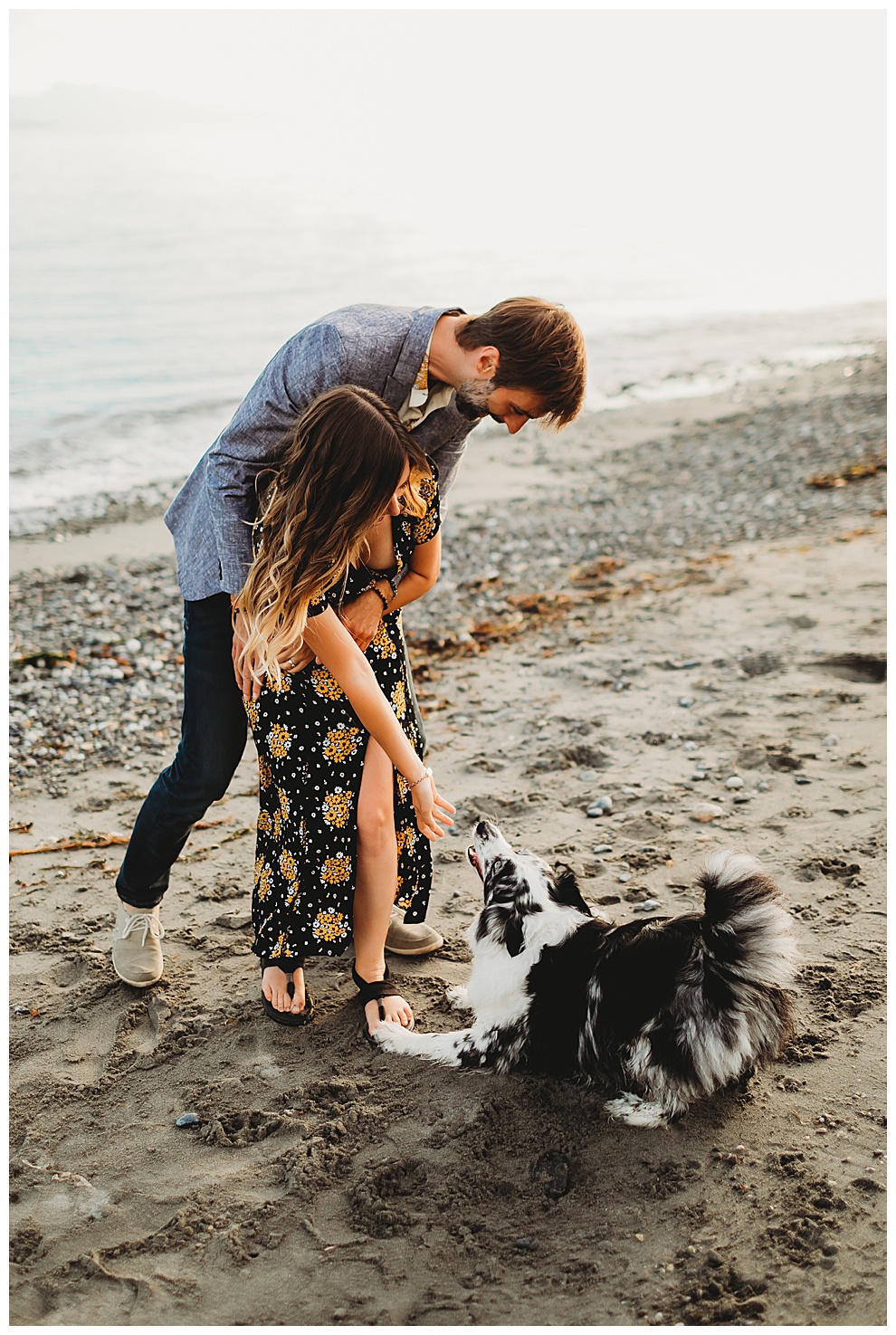couple hugging on beach as dog sits at their feet