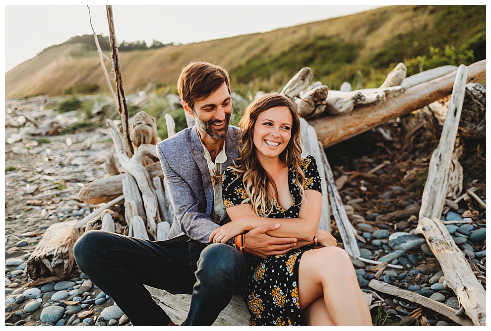 man and woman snuggle on beach during engagement shoot