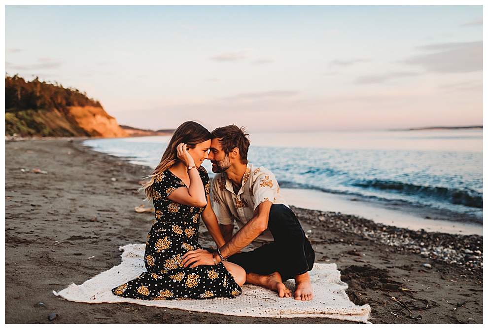 couple sitting on blanket on beach at sunset