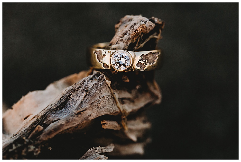 gold engagement ring with single large diamond and engraving of world map